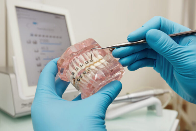 Prosthetics hands while working on the denture, false teeth, a study and a table with dental tools. Dental laboratory